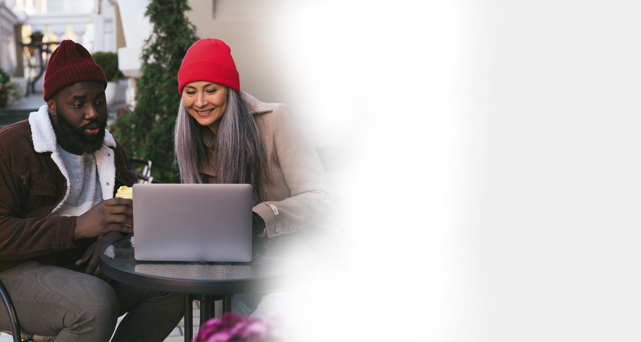 Man and Woman sitting outside looking at laptop